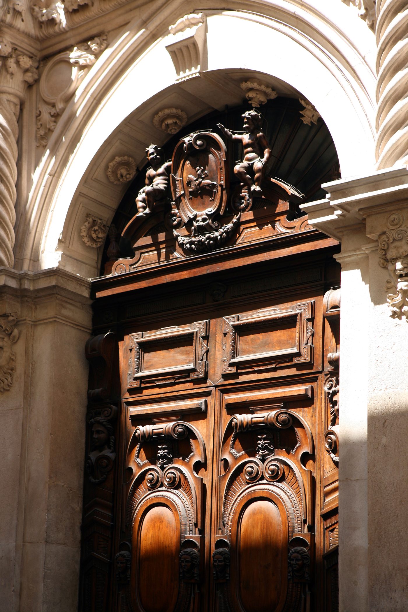 An ornate carved wooden doorway beneath a stone arch