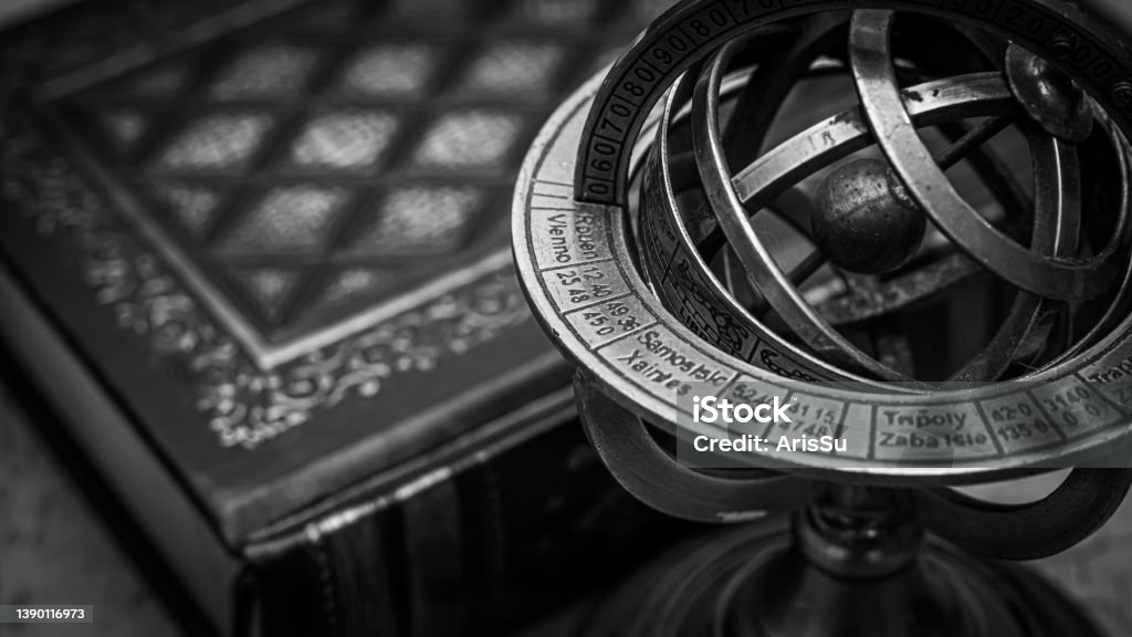 An antique armillary sphere beside an old leather-bound book